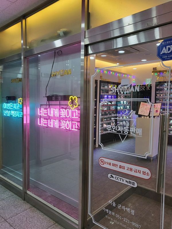 君子 アダルトグッズ店SHYMAN 君子駅店の出入口、ネオンサインと24時間無人自動販売の案内